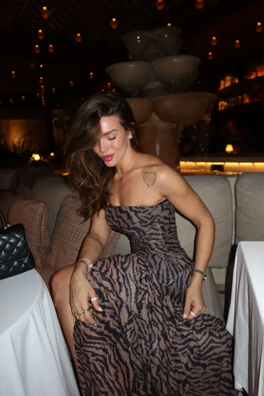 Gabryelle Pedroso in a candid seated moment wearing an animal-print evening dress