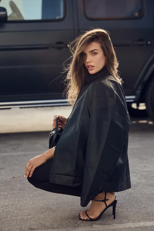 Gabryelle Pedroso seated in an elegant black blazer look beside a dark vehicle