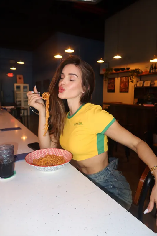 Gabryelle Pedroso wearing a yellow and green active top during a playful cafe moment